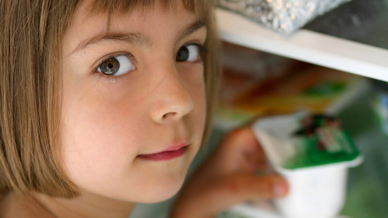 Nahaufnahme kleines Mädchen holt Joghurt aus Kühlschr