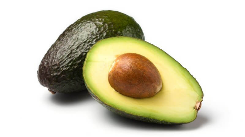 Eine ganze und eine halbe Avocado mit Kern
