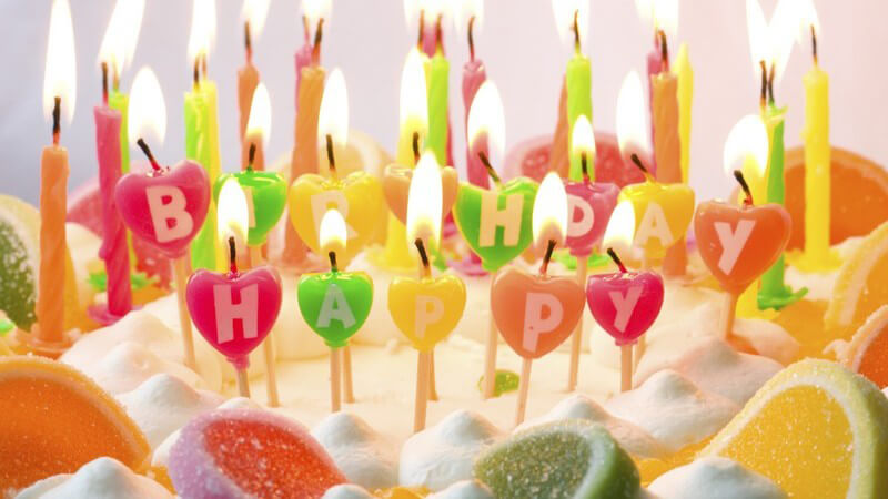 Bunte Happy Birthday-Kerzen auf Torte