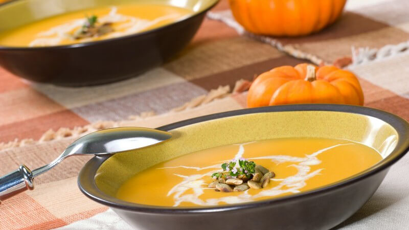 Gedeckter Tisch mit Kürbissuppe in Tellern