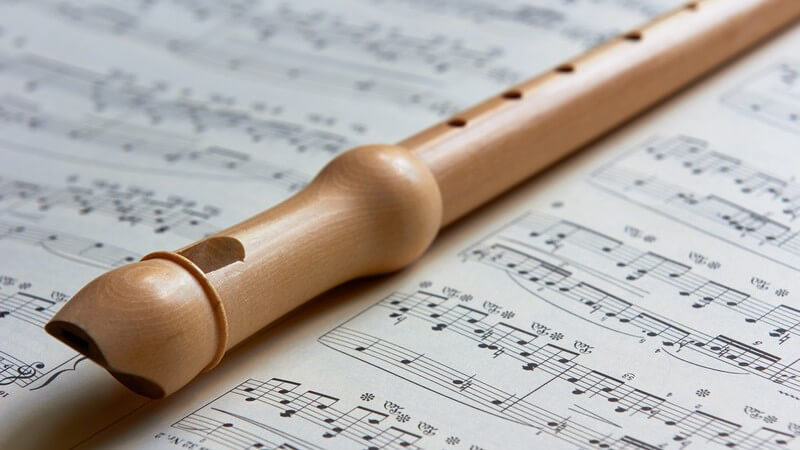 Hellbraune Blockflöte liegt auf einem Notenblatt
