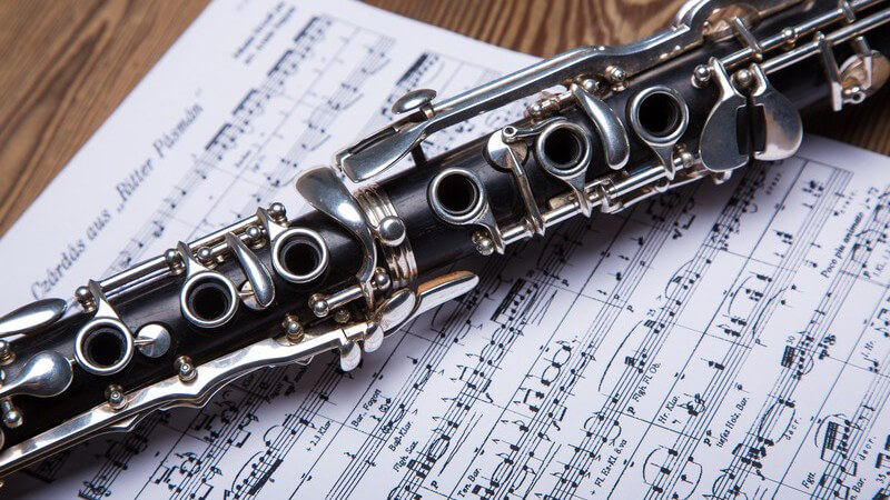 Schwarze Klarinette liegt auf einem Notenblatt auf einem Holztisch