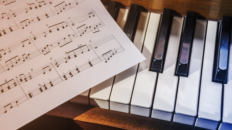 Notenblatt liegt auf den Tasten eines Klaviers