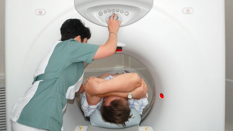 Ärztin schiebt Patient in Kernspintomographie Gerät