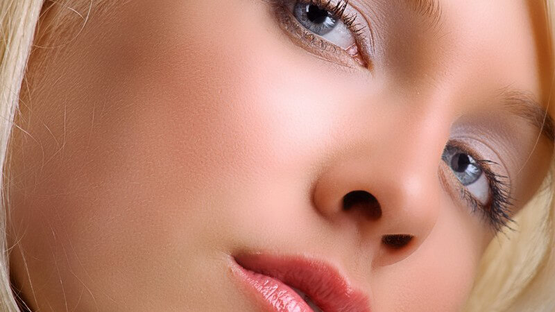 Nahaufnahme Frauengesicht, blonde Haare, blaue Augen, Kopf schräg nach rechts