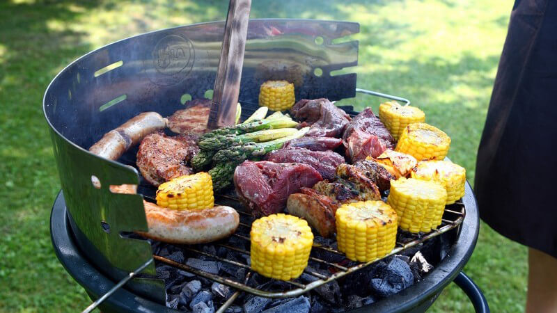 Grill auf Wiese mit Fleisch, Spargel, Maiskolben