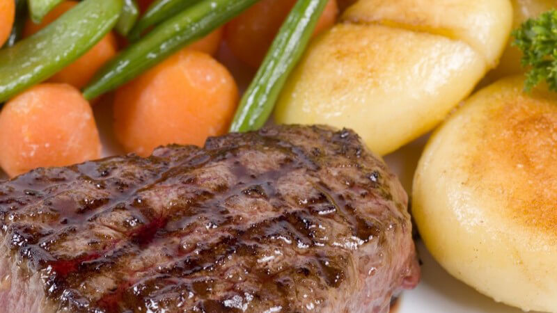 Nahaufnahme gegrilltes Steak neben Kartoffeln und Gemüse