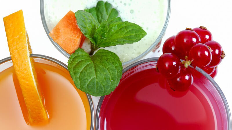 Ansicht von oben: drei Gläser mit Saft: Karotte, Johannisbeere, Orange