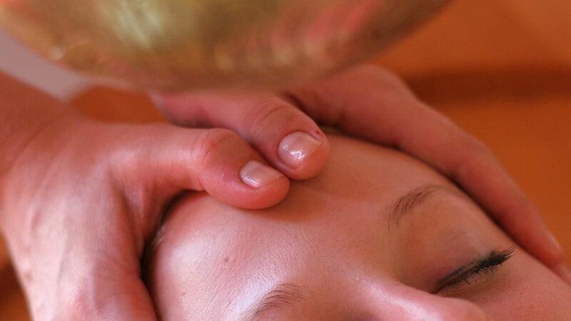 Shirodhara Massage, Stirn einer jungen Frau wird massiert