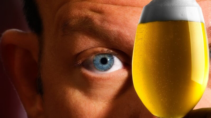 Mann hält ein frisch gezapftes Glas Bier vor sein Gesicht