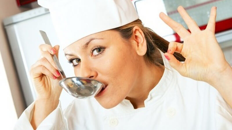 Kochen - Junge Köchin beim Abschmecken der Suppe