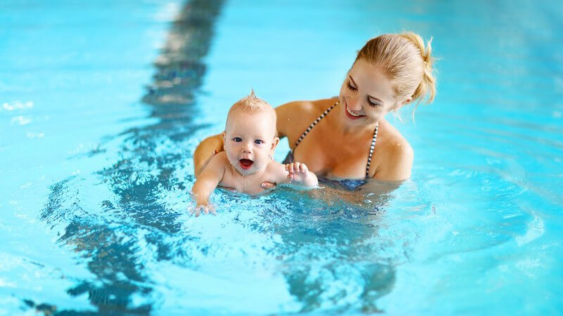 Blonde Mutter mit ihrem Baby beim Schwimmenlernen im Schwimmbecken
