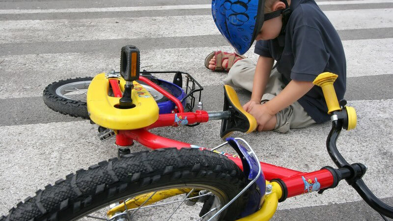 Kind ist mit dem Fahrrad gestürzt und fasst sich ans Knie