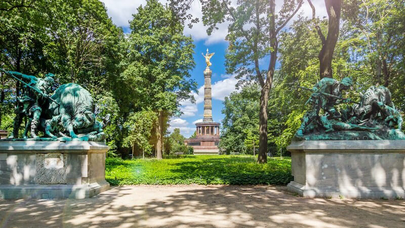 Blick zwischen zwei Statuen im Tiergarten hindurch auf die Siegessäule in Berlin