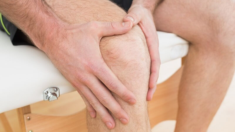 Knieschmerzen - Mann hält seine Hände an sein Knie