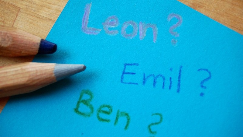 Blauer Zettel mit Jungennamen neben Buntstiften