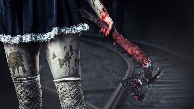 Frau (Zombie, Dämon) mit verdreckter Kleidung hält blutverschmierte Axt