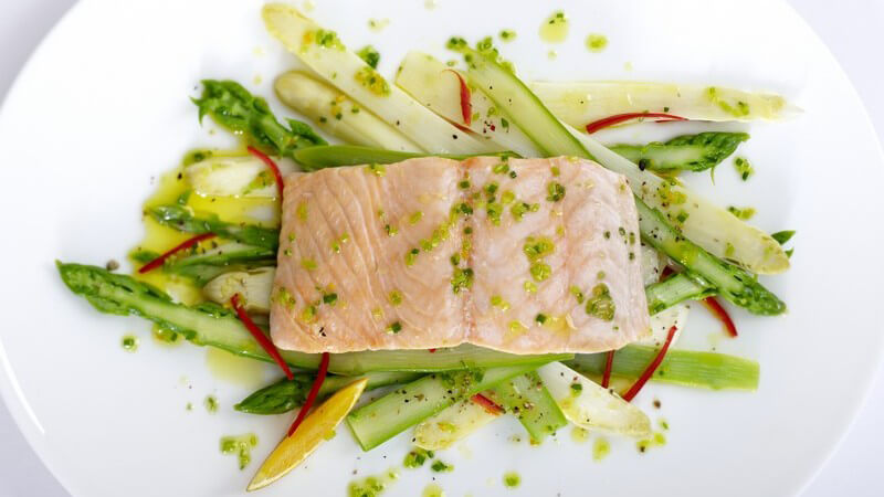 Ansicht von oben: Lachsfilet mit Spargel auf weißem Teller