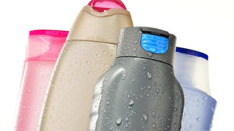Vier nasse Shampoo- und Duschgelflaschen vor weißem Hintergrund