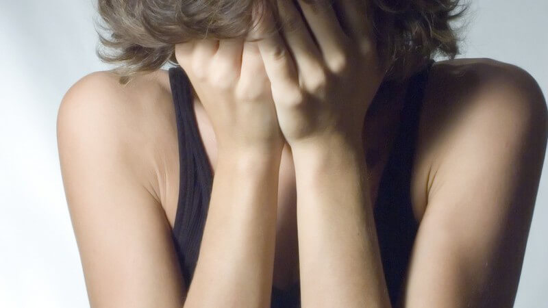 Junge hält sich beide Hände vors Gesicht, Angst