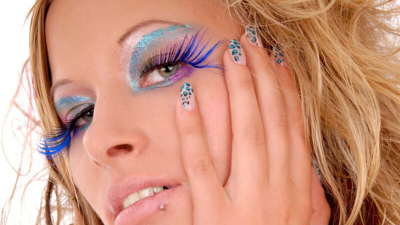 Blonde Frau mit bunten Wimpern, Lidschatten und bunten Nägeln