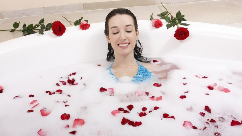 Junge Frau in Schaumbad mit Rosenblättern