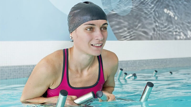 Frau mit grauer Badekappe beim Aqua-Biking im Schwimmbad