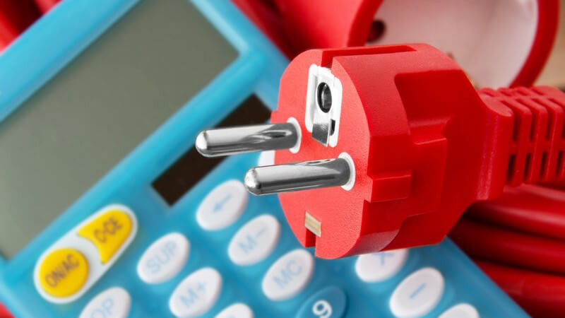 Roter Stromstecker auf blauem Taschenrechner