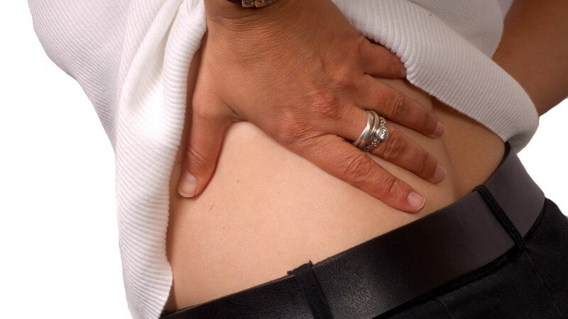 Nahaufnahme Frau legt Hand auf unteren Rücken, Rückenschmerzen