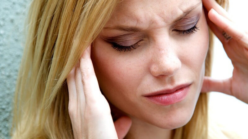 Gestresste Frau fasst sich an die Schläfen
