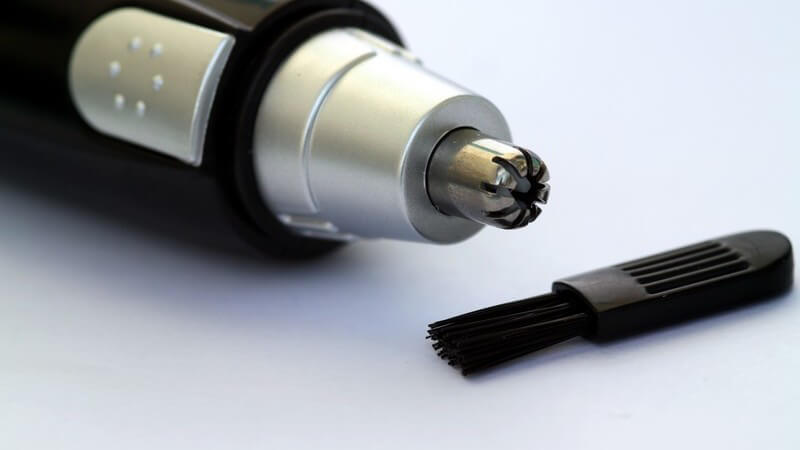 Ohren- oder Nasenhaarschneider, davor kleiner Pinsel zum Säubern