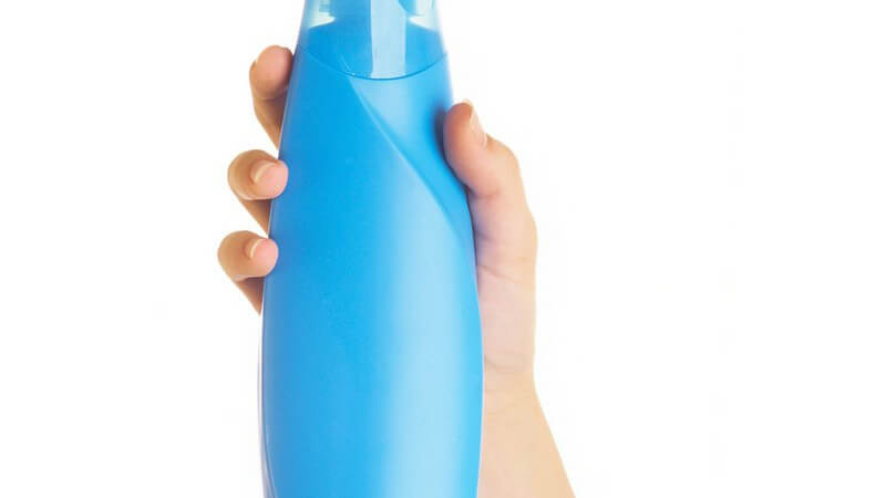 Frauenhände halten Kosmetikartikel in blauer Flasche in Kamera