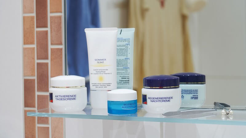 Kosmetikartikel auf Spiegelablage im Badezimmer