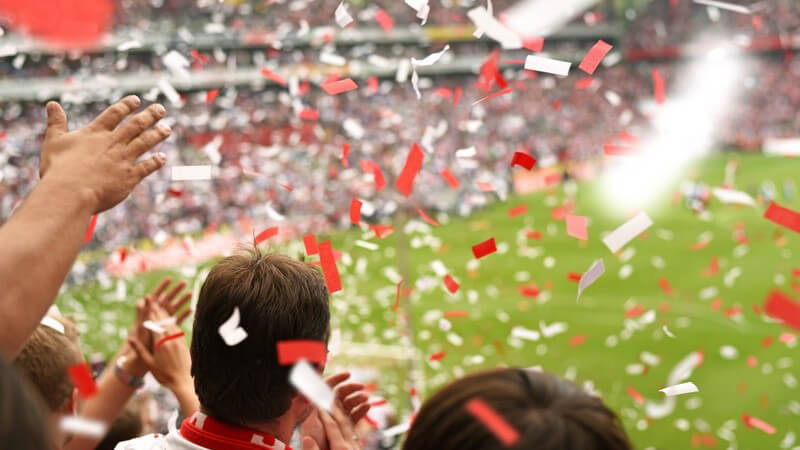 Blick von der Tribüne ins Stadion, rot-weiße Schnipsel regnen über die Zuschauer