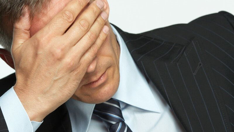 Geschäftsmann hält gestresst Hand vors Gesicht