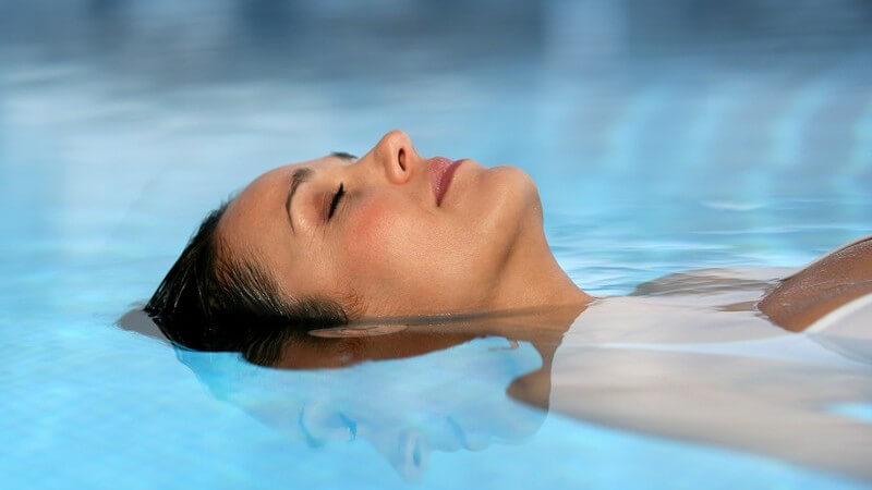 Frau liegt auf Rücken im Pool, entspannt