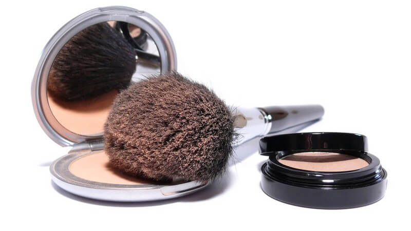 Nahaufnahme Puderpinsel, Puderdose und Spiegel auf weißem Hintergrund