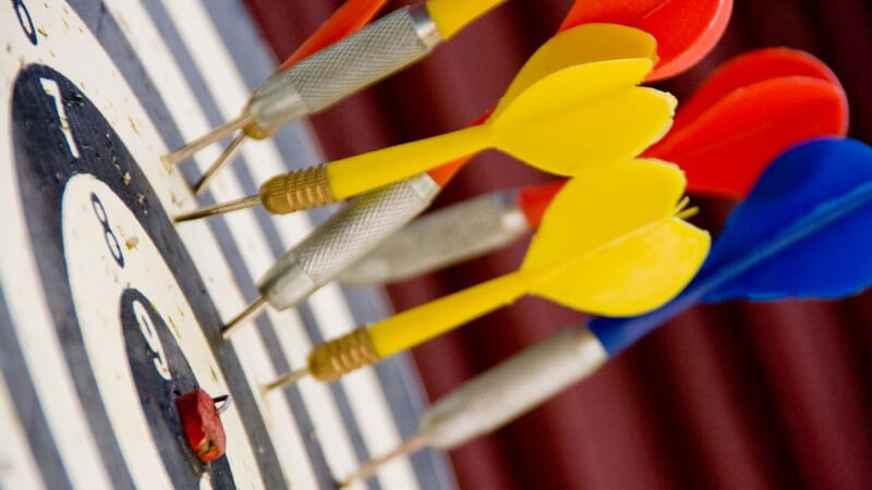 Bunte Dartfeile auf schwarz-weißer Dartscheibe