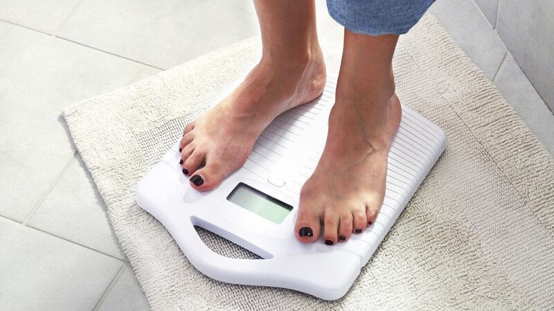 Ausschnitt Frauenfüße stehen auf einer Waage im Badezimmer