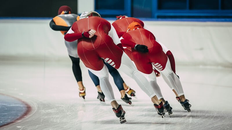 Rückansicht von vier Eisschnellläuferinnen in einer Kurve