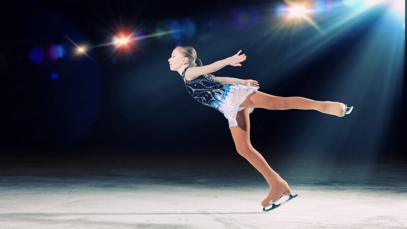 Junges Mädchen auf Schlittschuhen beim Eiskunstlauf fährt Pirouette