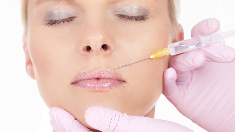 Frau erhält Spritze an der Lippe zur Faltenbehandlung