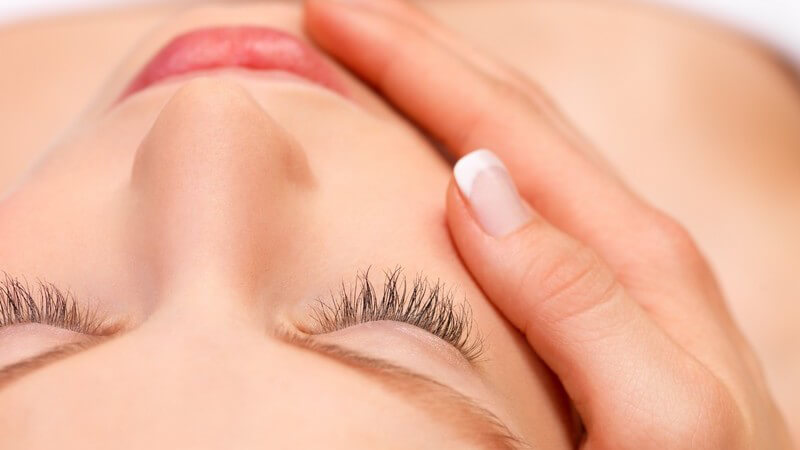 Frauengesicht von oben fotografiert, eine weibliche Hand massiert von rechts die Wange