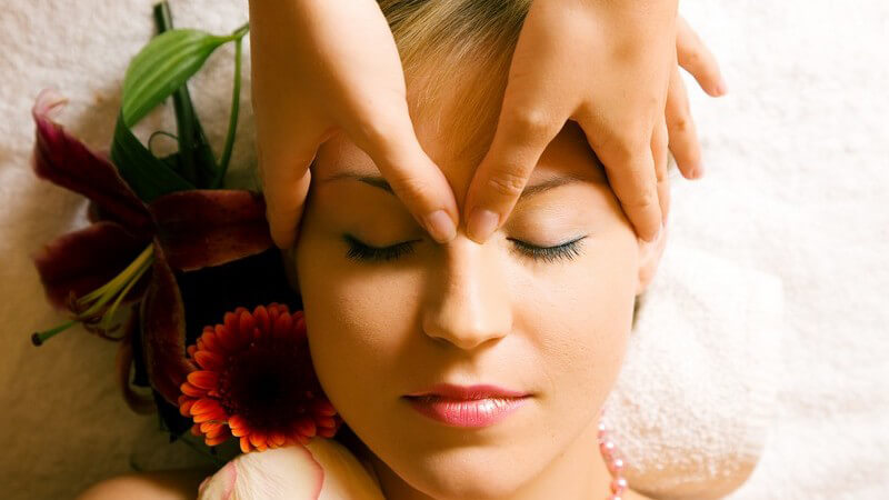 Kopf- und Gesichtsmassage bei einer hübschen Frau mit geschlossenen Augen