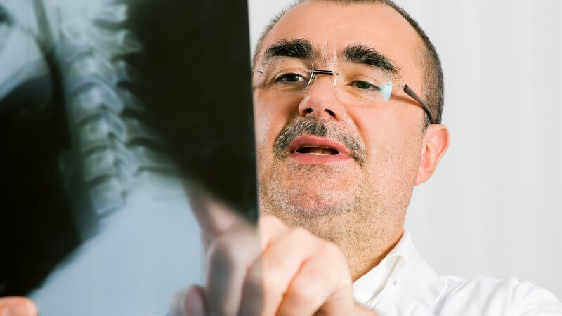 Arzt mit Brille betrachtet ein Röntgenbild der Wirbelsäule