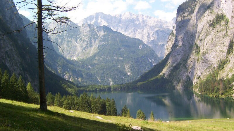 Naturaufnahme Gebirgsee umgeben von Bergen und Wiese