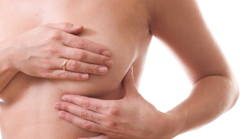 Frau tastet ihre Brust ab