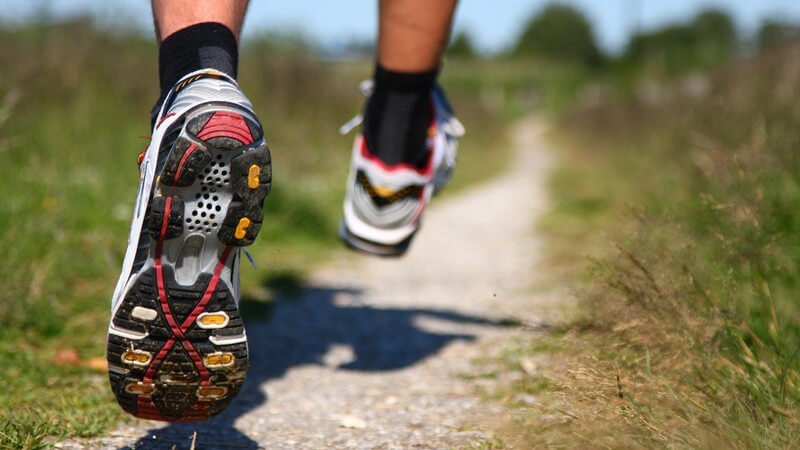 Joggen - Männerfüße beim Laufen, Laufschuhe auf Feldweg
