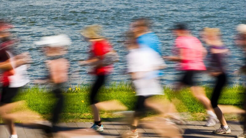 Gruppe von Joggern laufen am See entlang