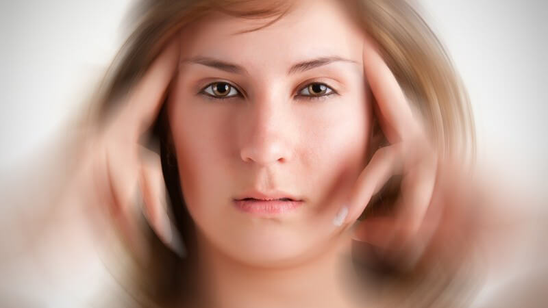 Junge Frau fasst sich an die Schläfen - Kopfschmerzen